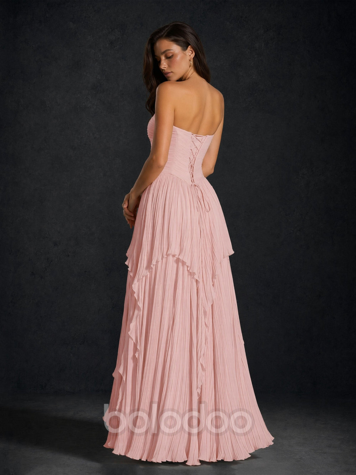 BOLODOO Blush Pink Pleated Chiffon Strapless Lace-Up Corset Back Tiered Ruffle Maxi Dress - Front Seated View Showing Tiered Ruffle Skirt Detail | BOLODOO watermark