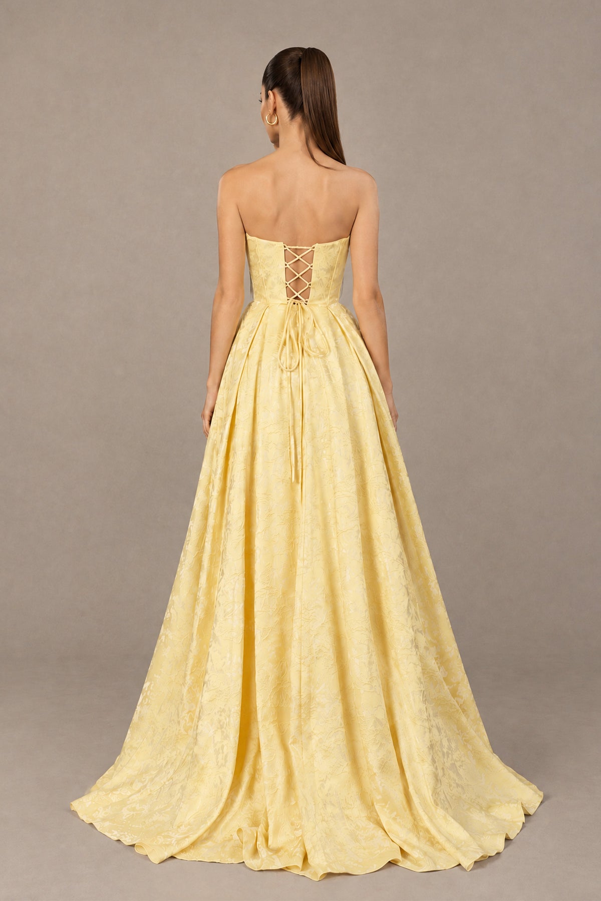Back view of BOLODOO yellow strapless prom dress with adjustable lace-up back and sweep train