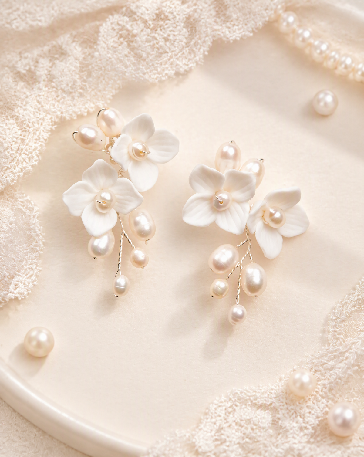 Close view of BOLODOO ivory floral earrings showing shaped petals and dangling pearl-look beads