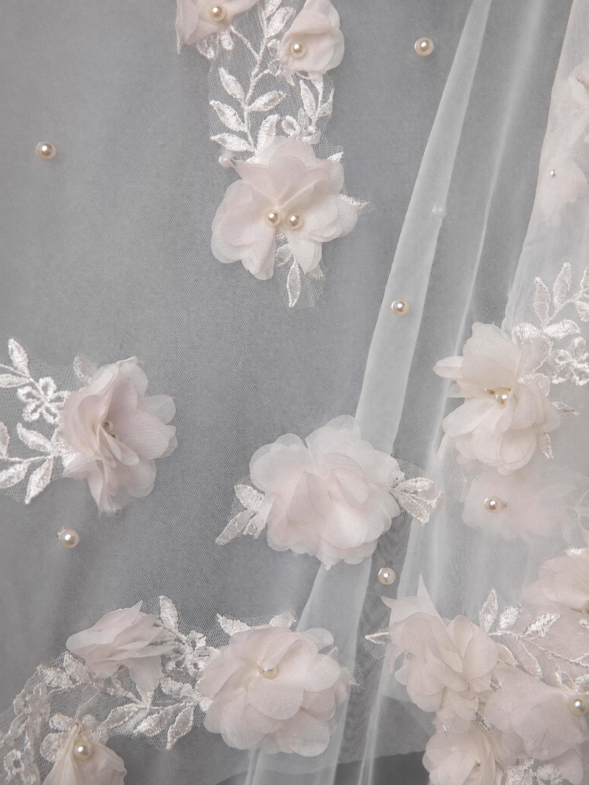 Close-up of dimensional flower appliques, embroidered leaves and pearl-look beads on BOLODOO bridal veil