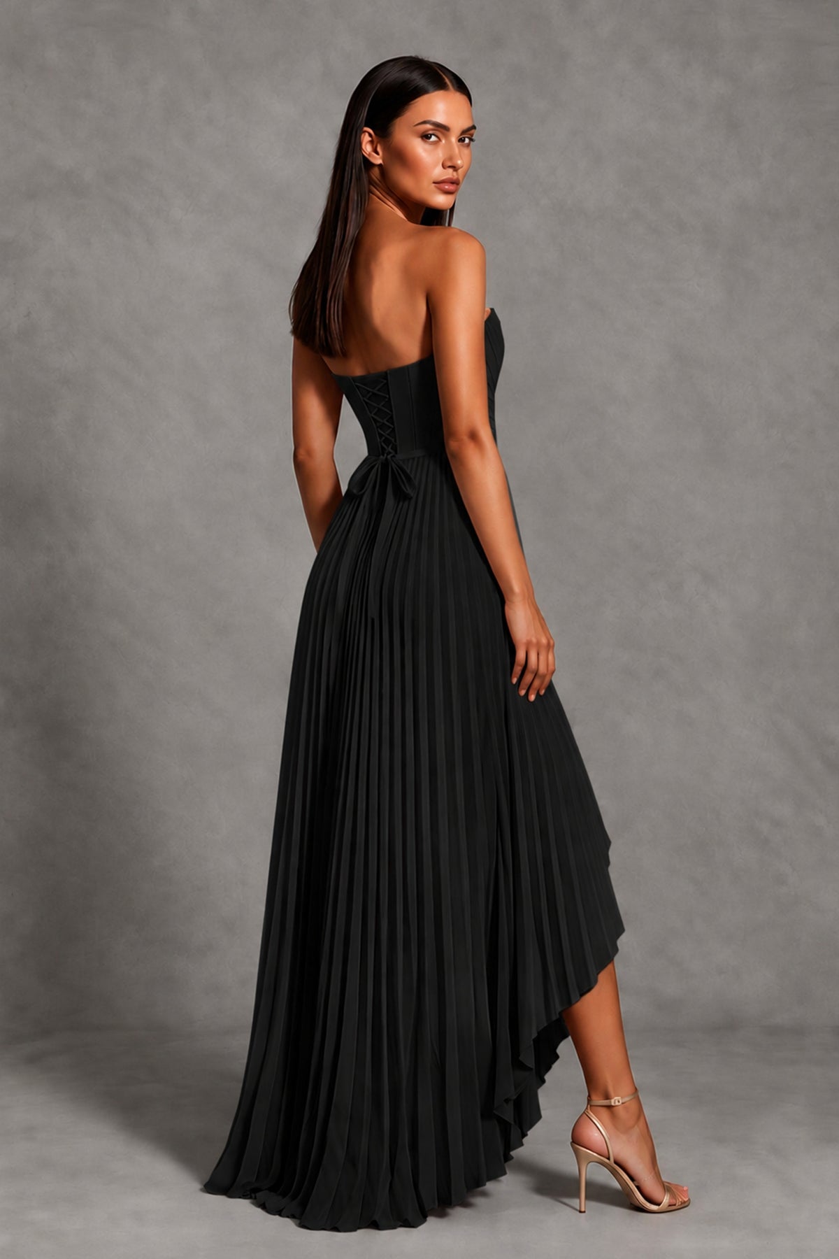 Back view of black strapless pleated evening gown with long high-low skirt
