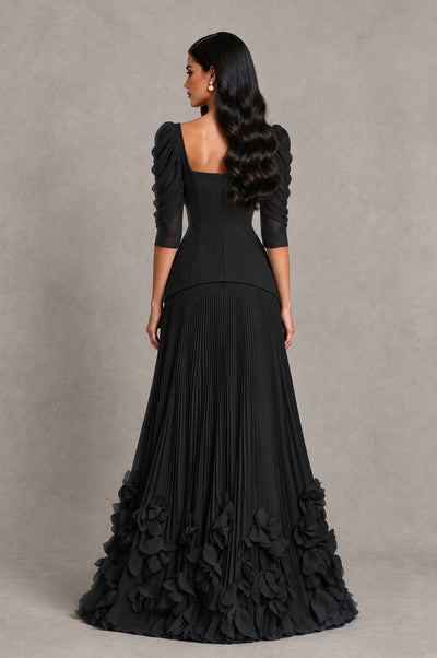 Black square-back evening dress with pleated skirt and petal-like floral ruffles, rear view