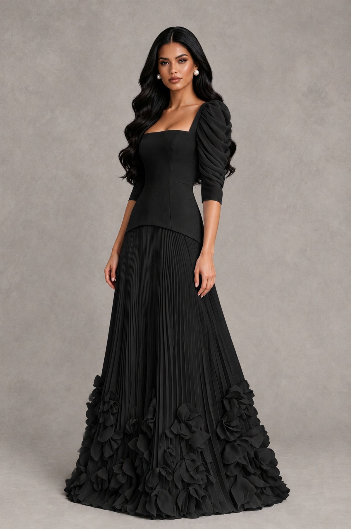 Black pleated A-line evening gown with three-quarter puff sleeves and dimensional floral hem, angled front view
