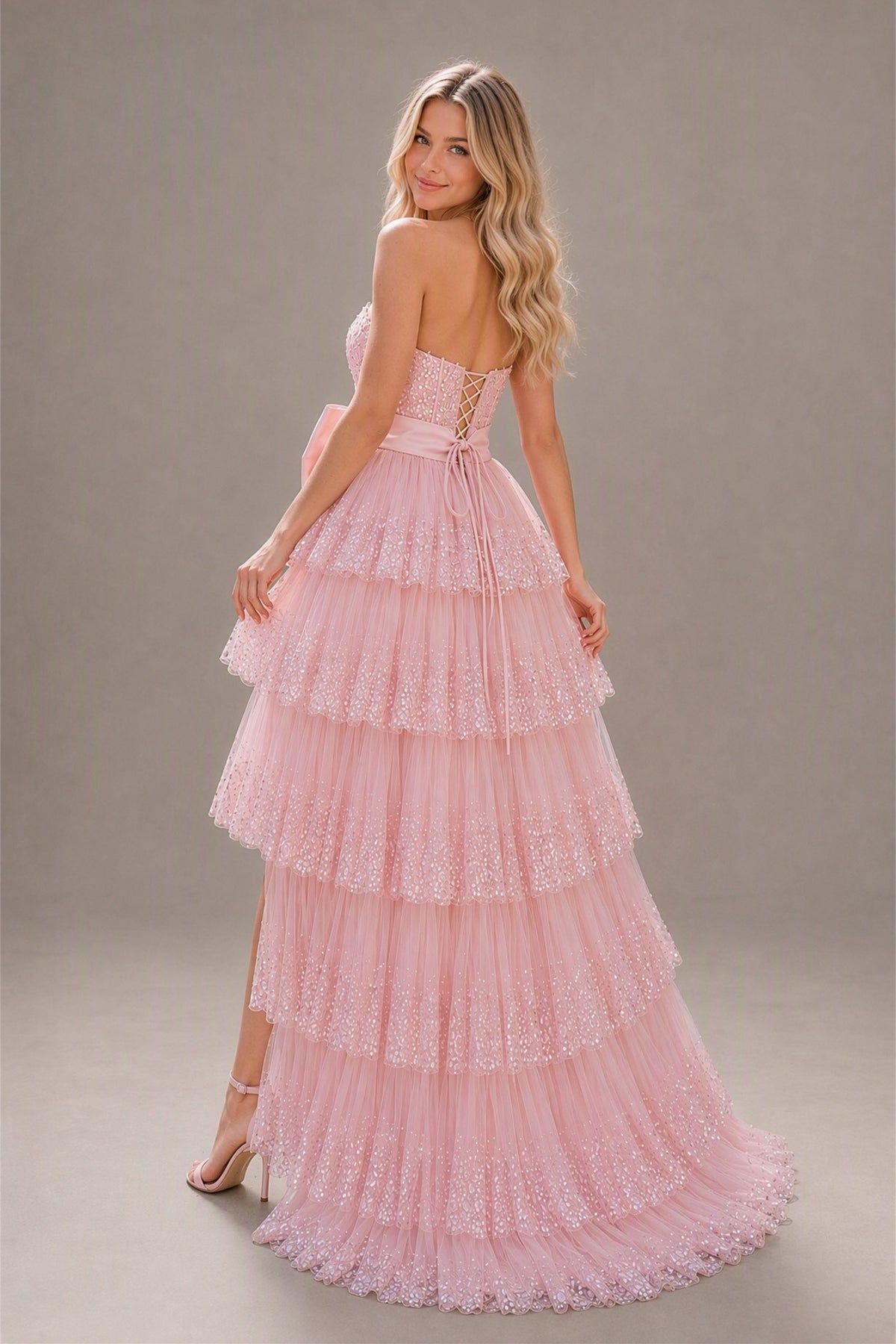 BOLODOO blush pink strapless prom dress showing lace-up open back and trailing tiered hem