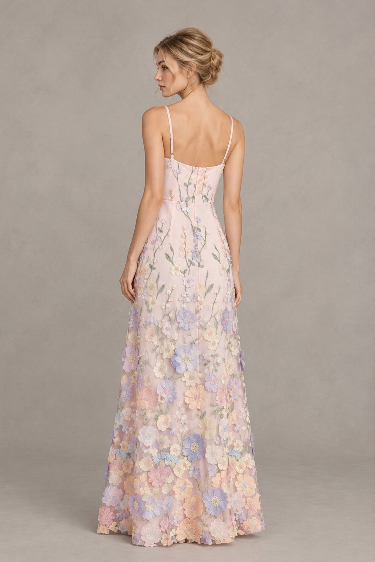 Front view of a woman in a blush pink spaghetti strap maxi dress with 3D floral appliques