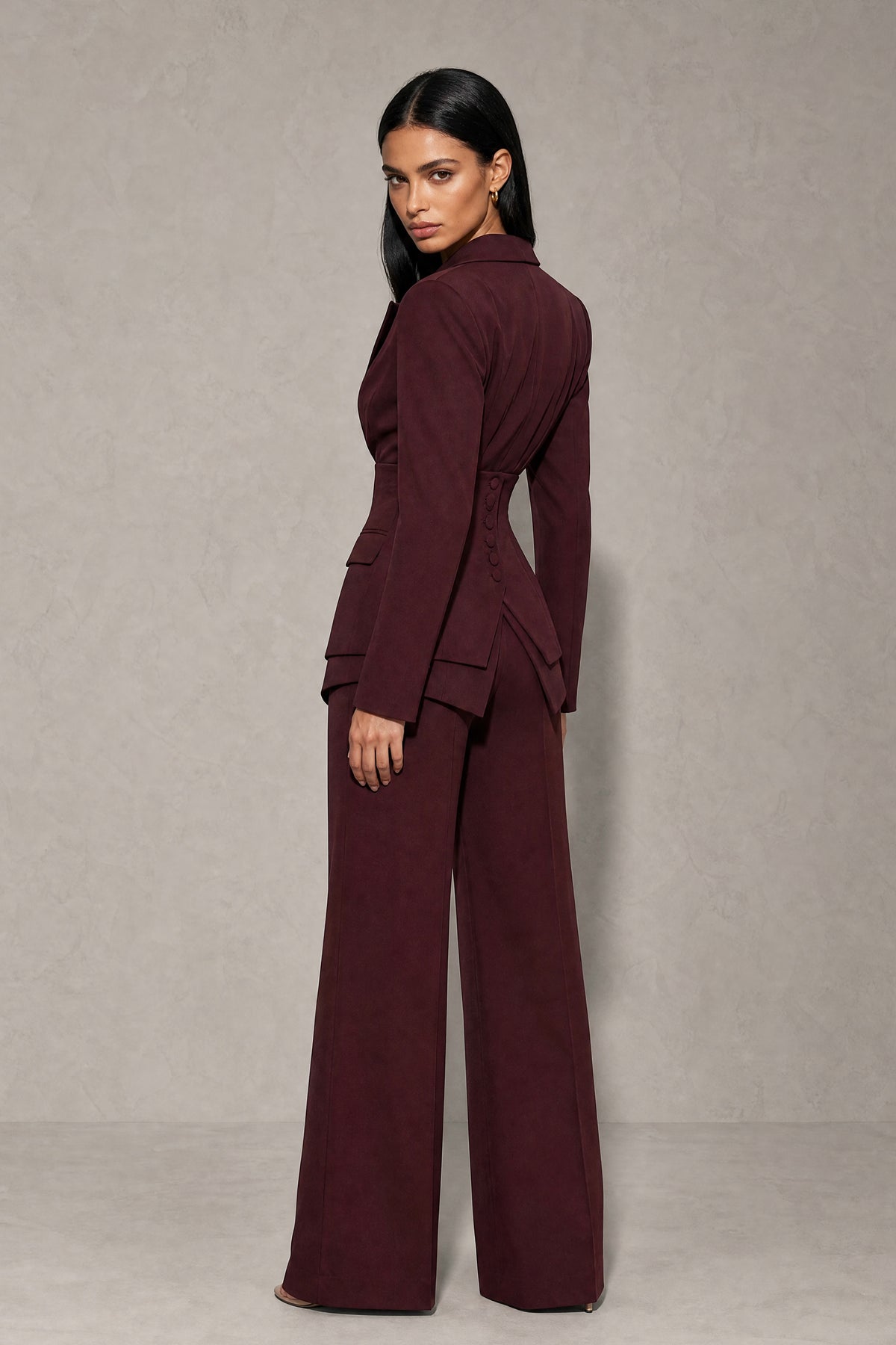 Back view of burgundy covered back blazer with layered peplum flaps and wide leg pants