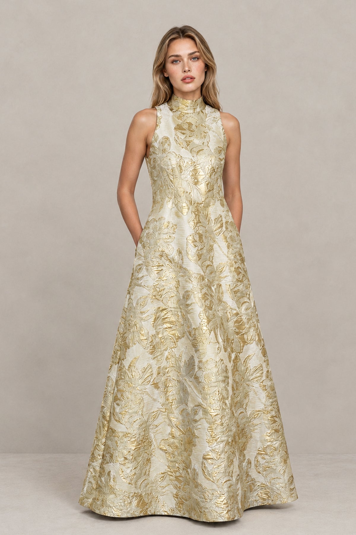 BOLODOO champagne and gold floral jacquard high neck sleeveless A-line maxi dress, front view with hands in side pockets