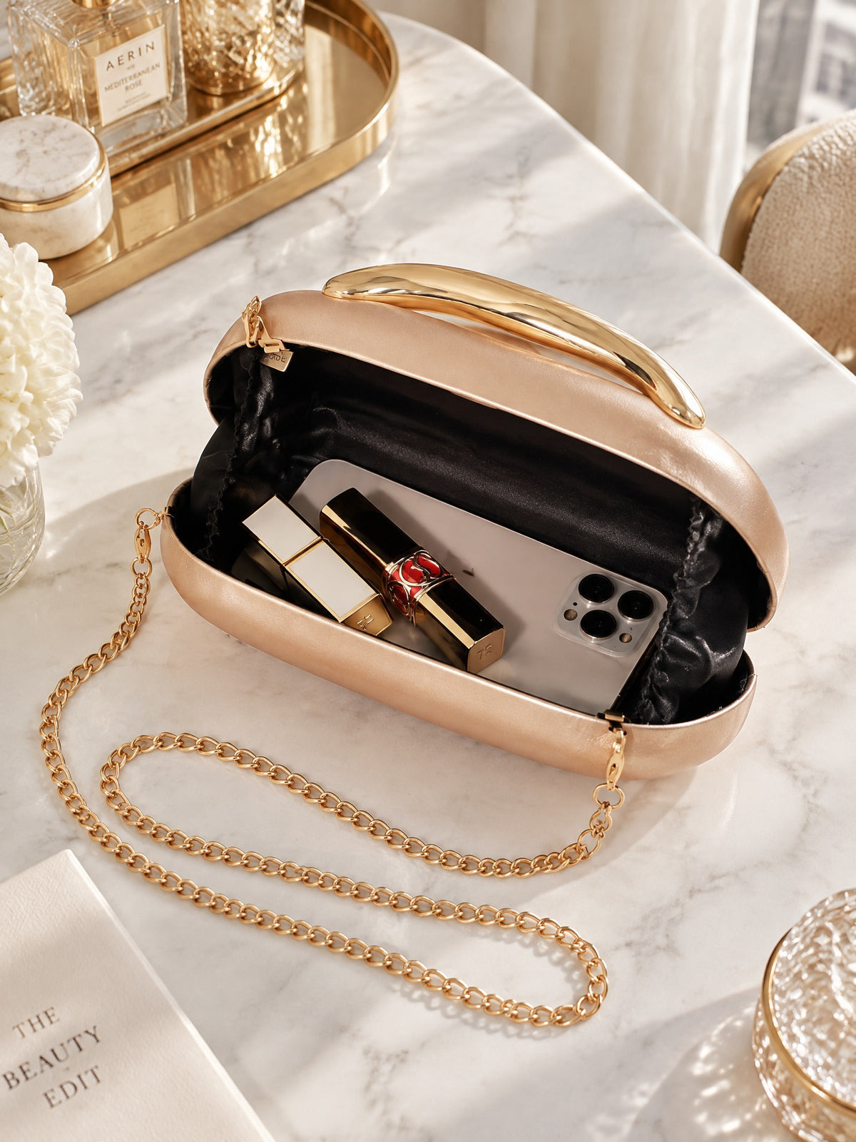Open BOLODOO champagne clutch showing dark lining and gold-tone chain