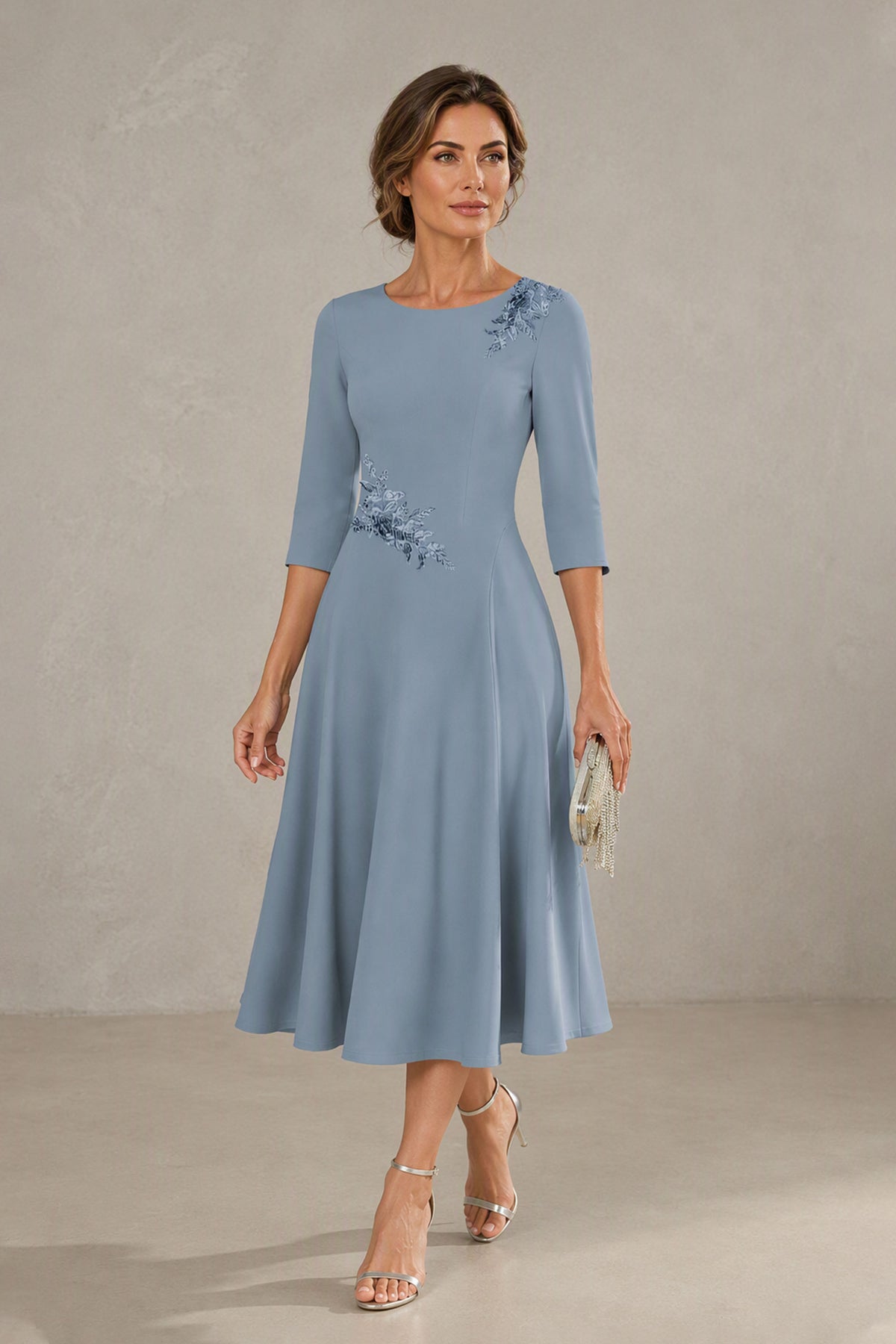 Dusty blue midi wedding guest dress styled with beaded clutch and gold heels, front view