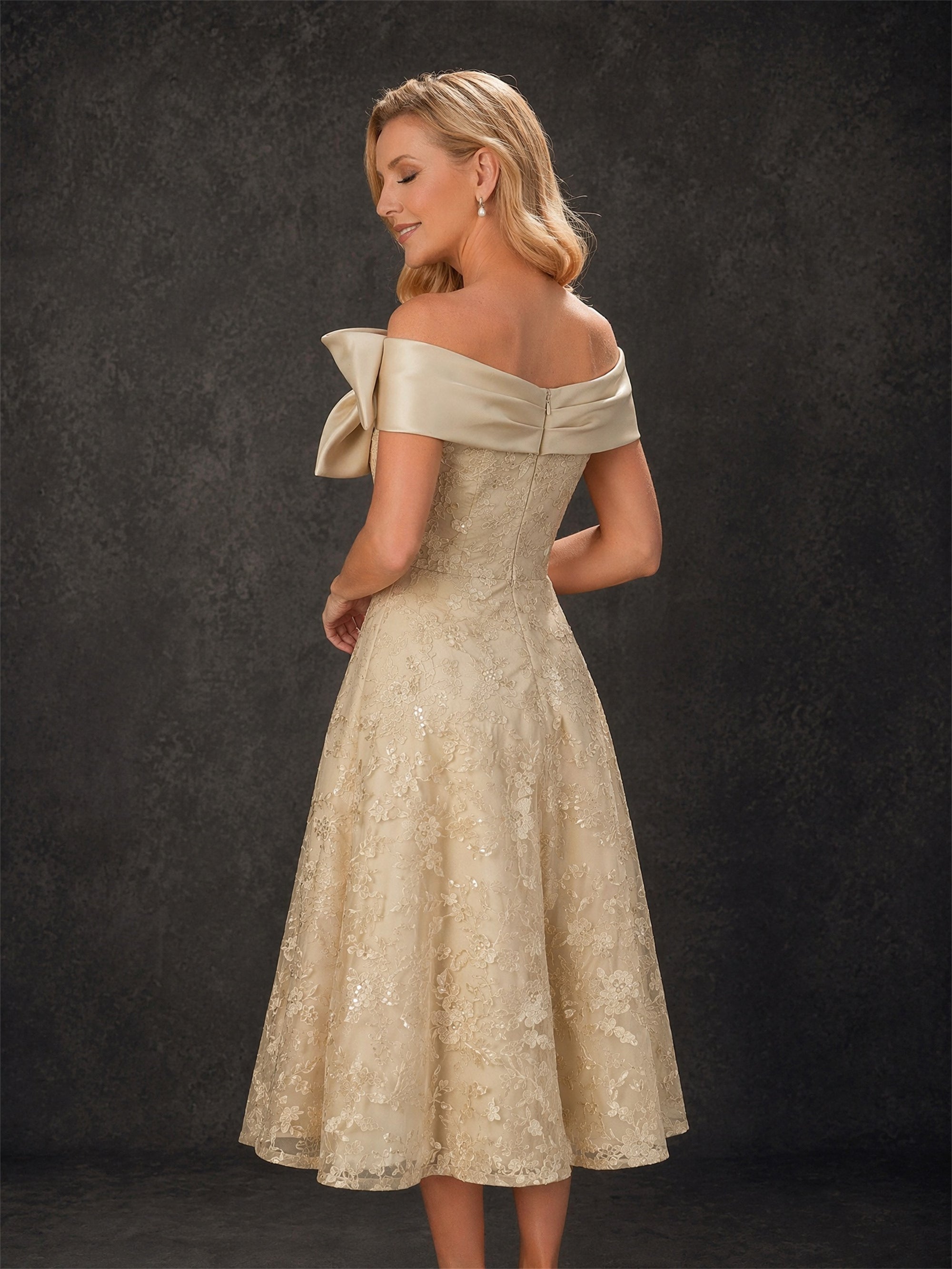 BOLODOO champagne gold lace off-shoulder bow tea-length dress - three-quarter front view with clutch