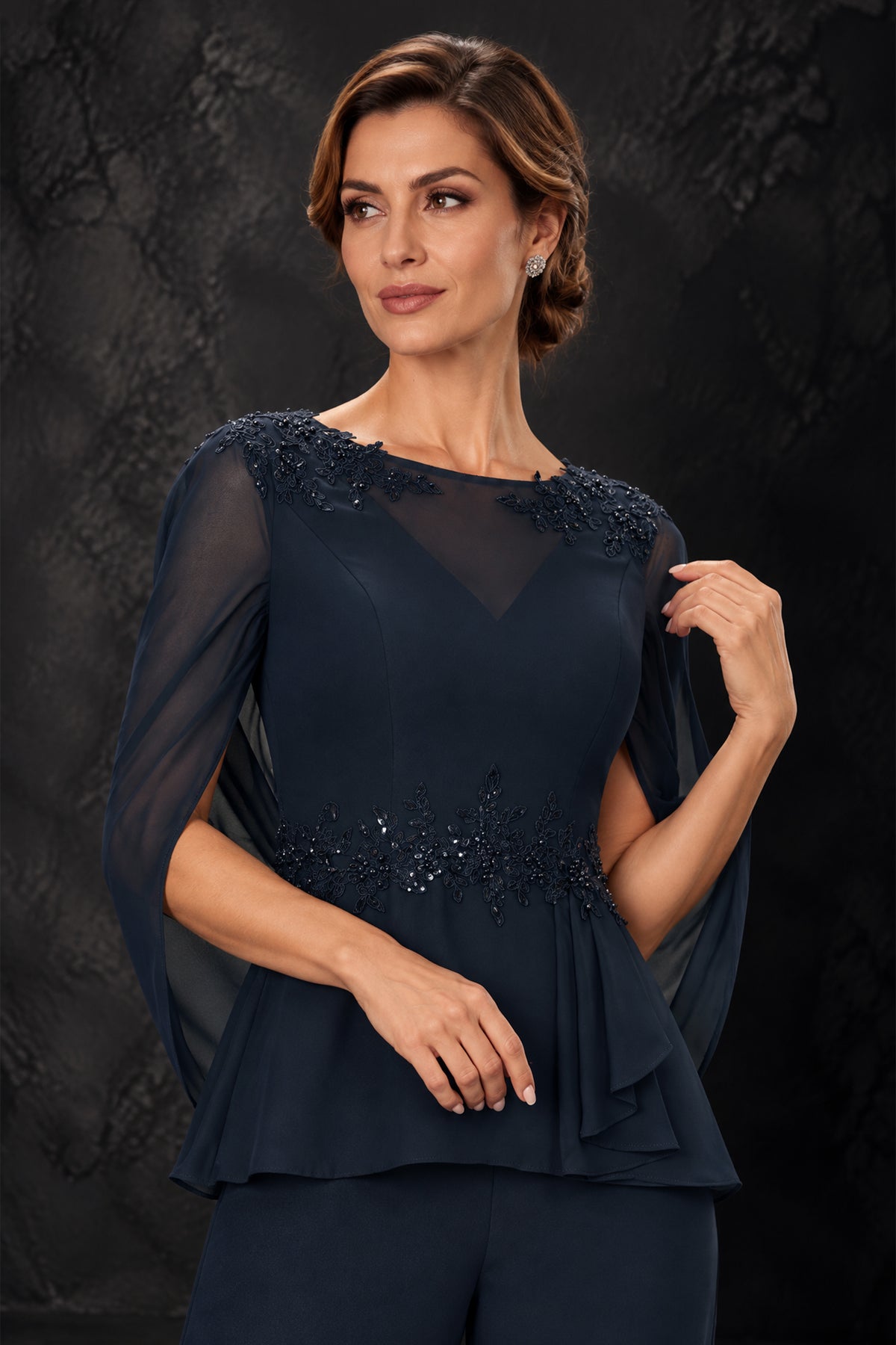 Close-up of navy blue pantsuit with floral shoulder and waist embellishments and sheer cape sleeves