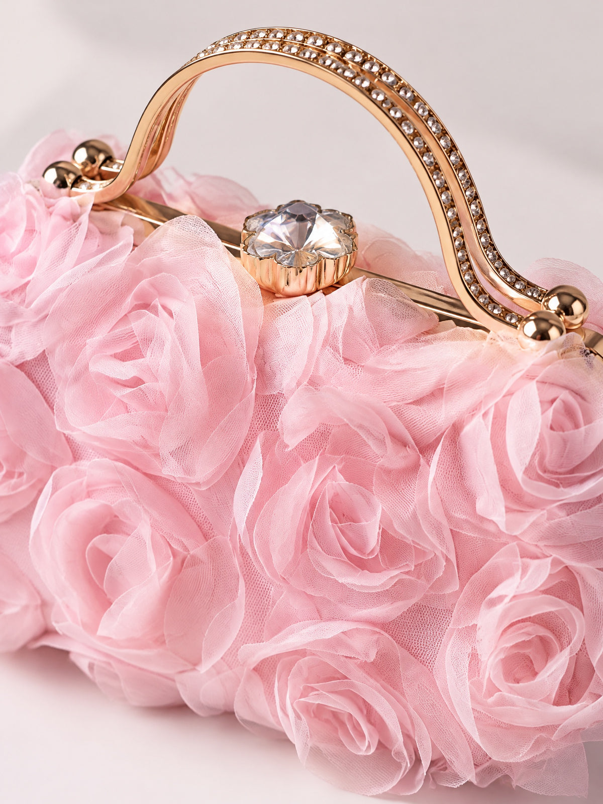 Close-up of pink fabric roses, sparkling handle and faceted clasp on BOLODOO evening bag