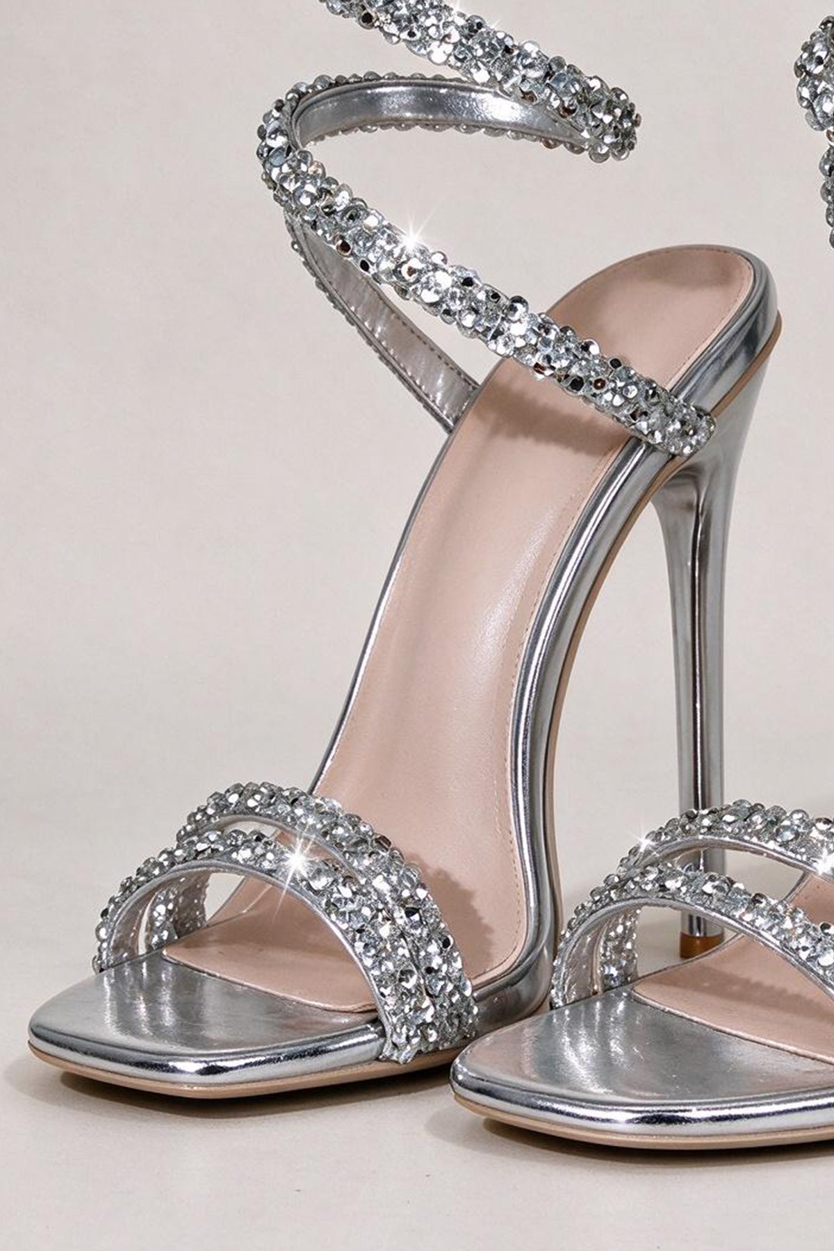 Close-up of BOLODOO silver sandals showing crossed rhinestone toe straps and metallic finish